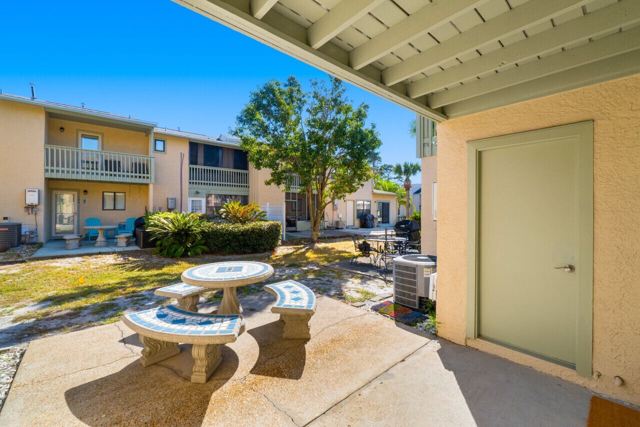 A courtyard with outdoor seating, a covered patio, and a building with balconies.