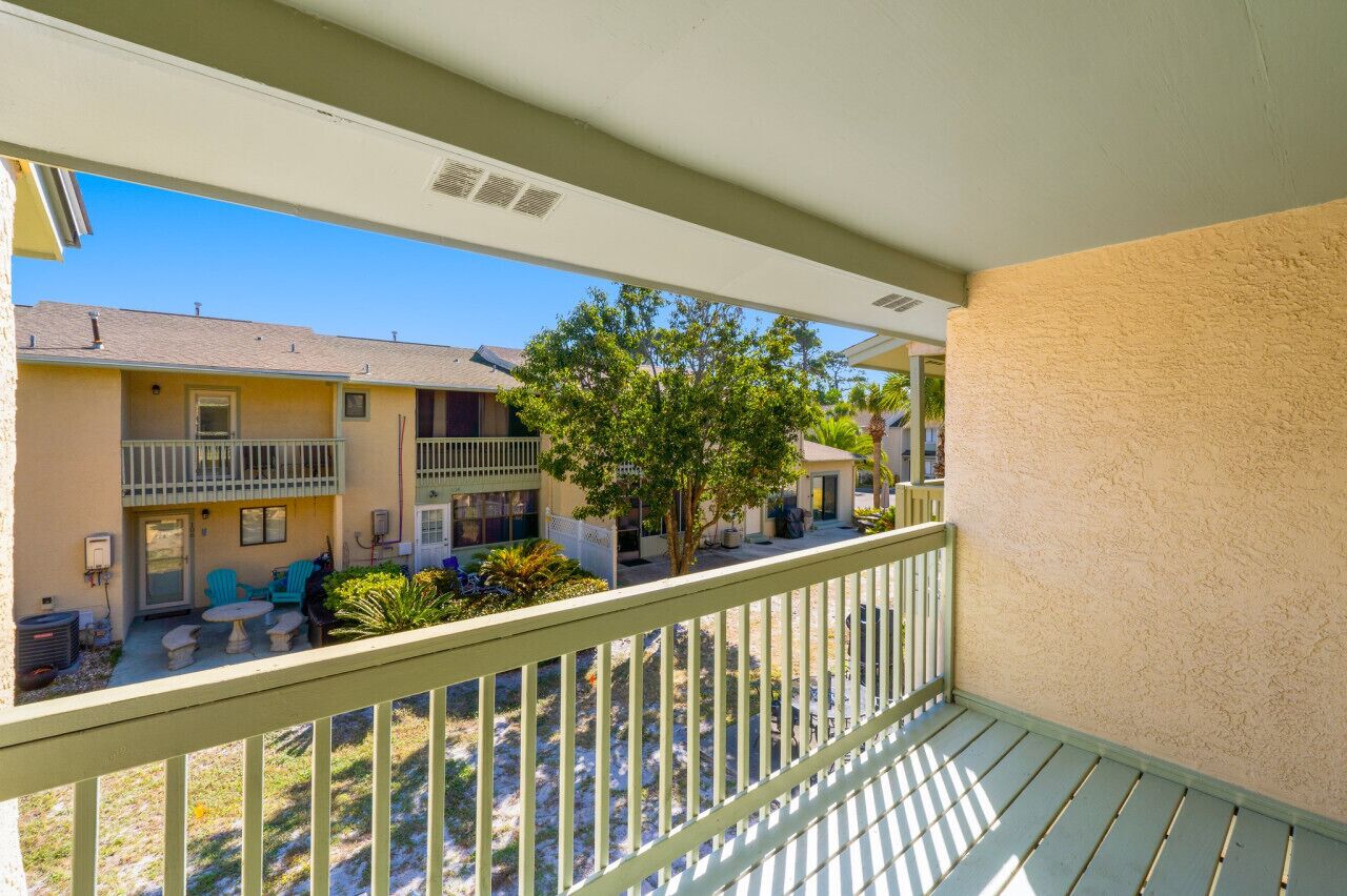 A balcony with a view of neighboring buildings and a tree.