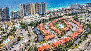 Vista aérea de una zona turística costera con un complejo circular central, un puerto deportivo y altos hoteles en el fondo.