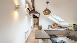 Una cocina moderna con tragaluz, vigas de madera y una lámpara colgante.