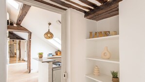 Una cocina moderna con armarios blancos, techo de madera y una lámpara colgante.