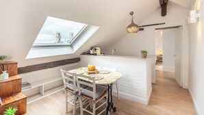 Un loft moderno con comedor, cocina y un amplio tragaluz.