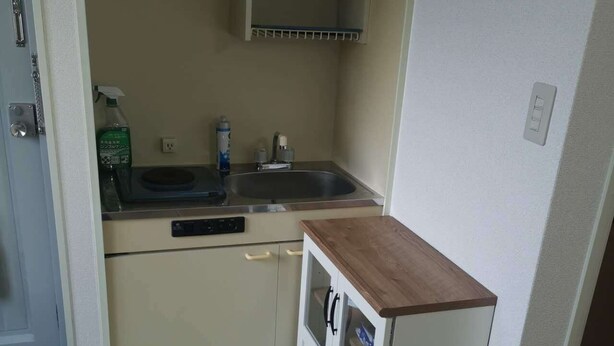 A compact kitchen with a sink, a microwave, and a small cabinet with a wooden countertop. - Shin Awaji Building II 202  (Osaka)