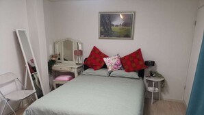 A bedroom with a bed, a dresser, a mirror, a nightstand, and a small table. - Shin Awaji Building II 202  (Osaka)
