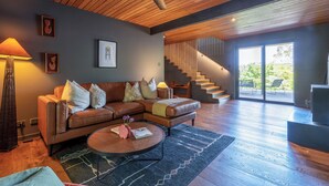 Ein modernes Wohnzimmer mit einem braunen Ledersofa, einem runden Couchtisch und einer Treppe, die zu einem Außenbereich führt.