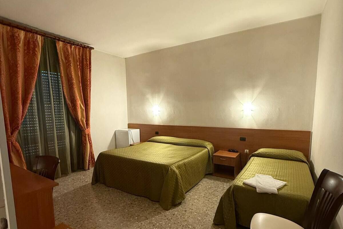 Une chambre d’hôtel avec deux lits, une chaise, une petite table et un escalier.