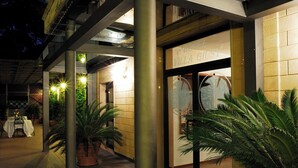 L’entrée d’un hôtel, avec un espace extérieur abrité, des plantes en pot et une enseigne indiquant « HÔTEL VILLA GUSSY ».