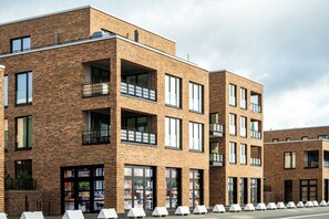 Un edificio de varios pisos con fachada de ladrillo, ventanas grandes y balcones.