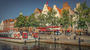Un bateau nommé « Lübeck » était amarré au bord de l’eau, avec des bâtiments en arrière-plan.