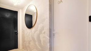 Una habitación de hotel con una puerta negra, un espejo redondo y una pared con un diseño discreto.