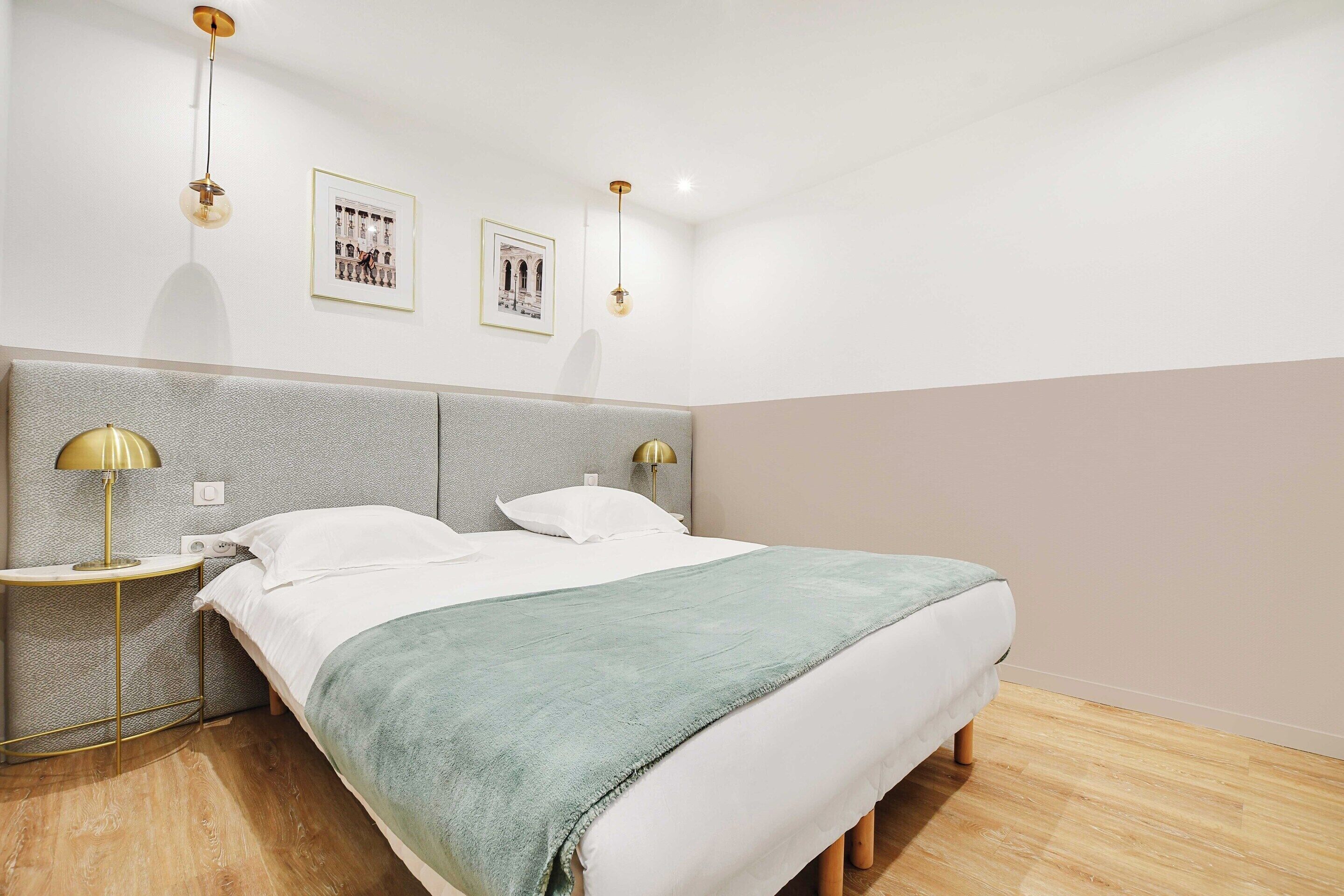 A modern bedroom with a bed, two bedside tables, and two wall-mounted lamps.