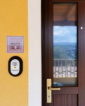 A door with a keypad lock and a view of a balcony with a railing. - Tiny Shell House (Piran)