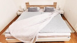 A neatly made bed with striped bedding, two pillows, and a blanket. - Tiny Shell House (Piran)