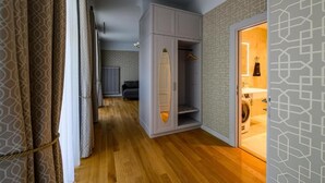 A hallway with a grey wardrobe, a hanging wardrobe, and a washing machine visible through an open door. - Roze Kūrmājas Residence (Liepaja)