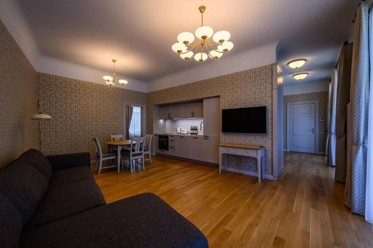 Una sala de estar moderna con sofá, una mesa de comedor con sillas, una zona de cocina y un televisor montado en la pared.