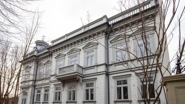 A large, white, multi-story building with a symmetrical facade, featuring multiple windows and a central balcony. - Roze Kūrmājas Residence (Liepaja)