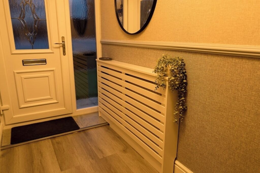A hallway with a white door, a radiator, and a mirror on the wall.