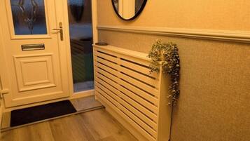 A hallway with a white door, a radiator, and a mirror on the wall.