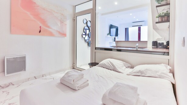 Een moderne hotelkamer met een groot bed, een zichtbare badkamer achter een glazen deur en een spiegel aan de muur.