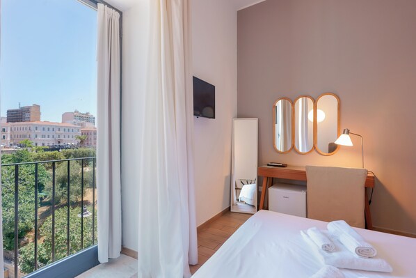 A hotel room with a bed, a desk, a chair, a TV, and a balcony with curtains. - Casa Matilde (Taranto)