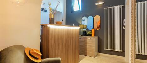 A modern interior with a wooden reception desk, a mirror, and a radiator.