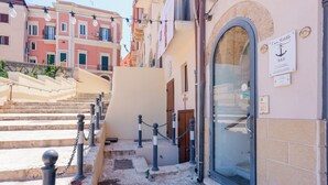 L’entrée d’un hôtel, avec une porte fermée à clé et protégée par une chaîne, un escalier menant à l’entrée et une enseigne indiquant qu’il s’agit d’un hôtel proposant également un service de chambre et de petit-déjeuner.