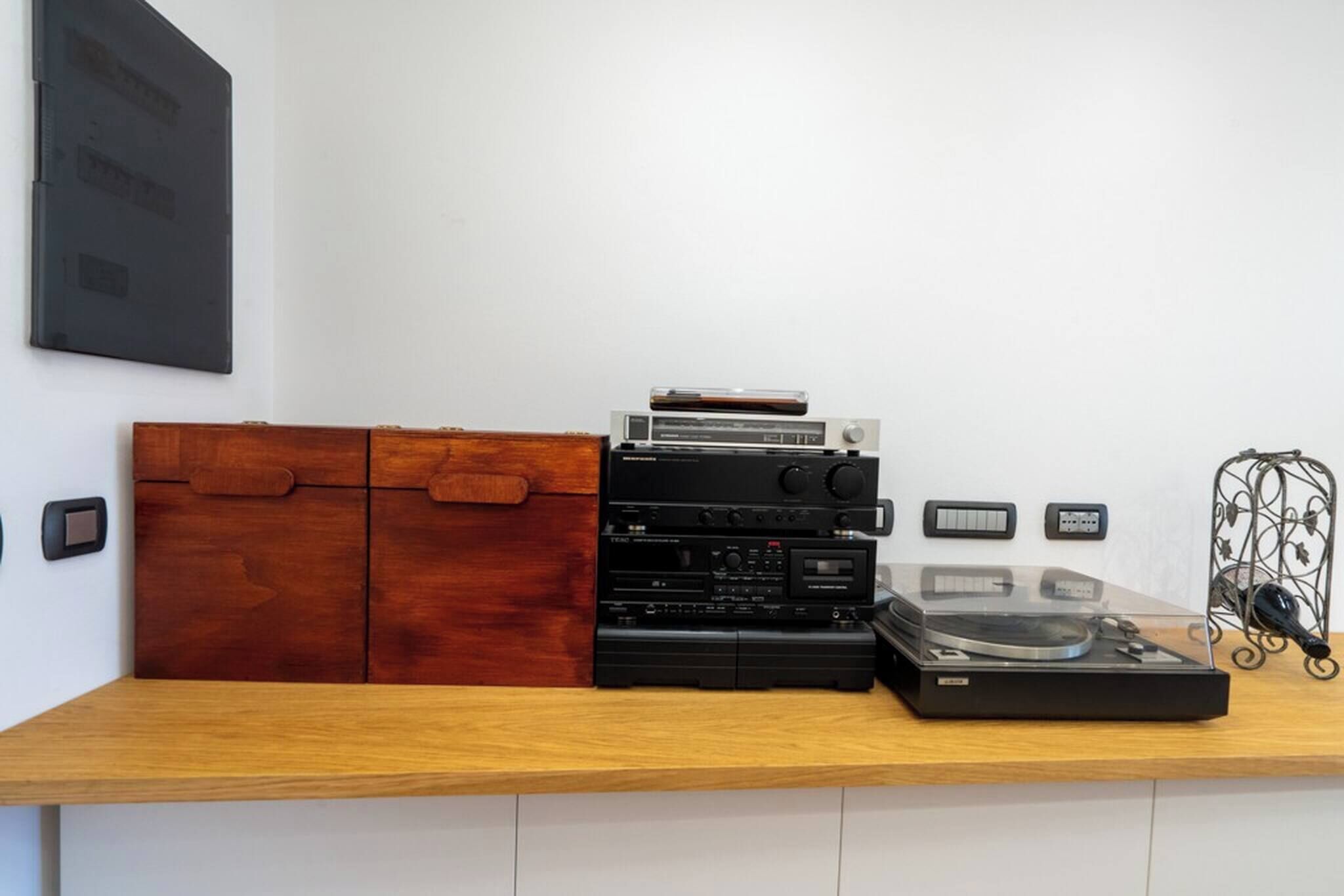 A wooden counter with audio equipment, including a turntable and amplifiers, against a white wall.