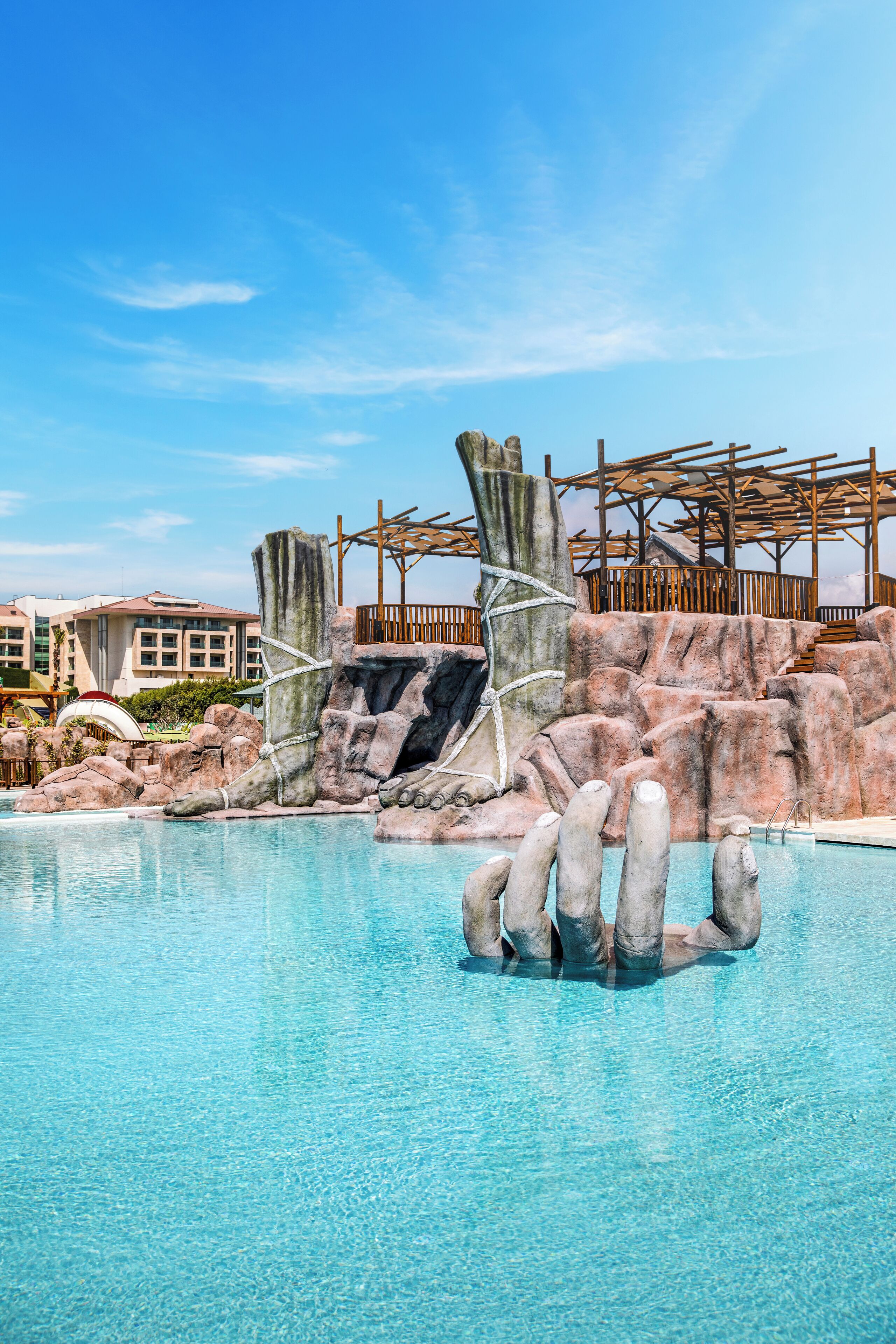 A swimming pool with clear blue water, surrounded by rocky formations and wooden structures.