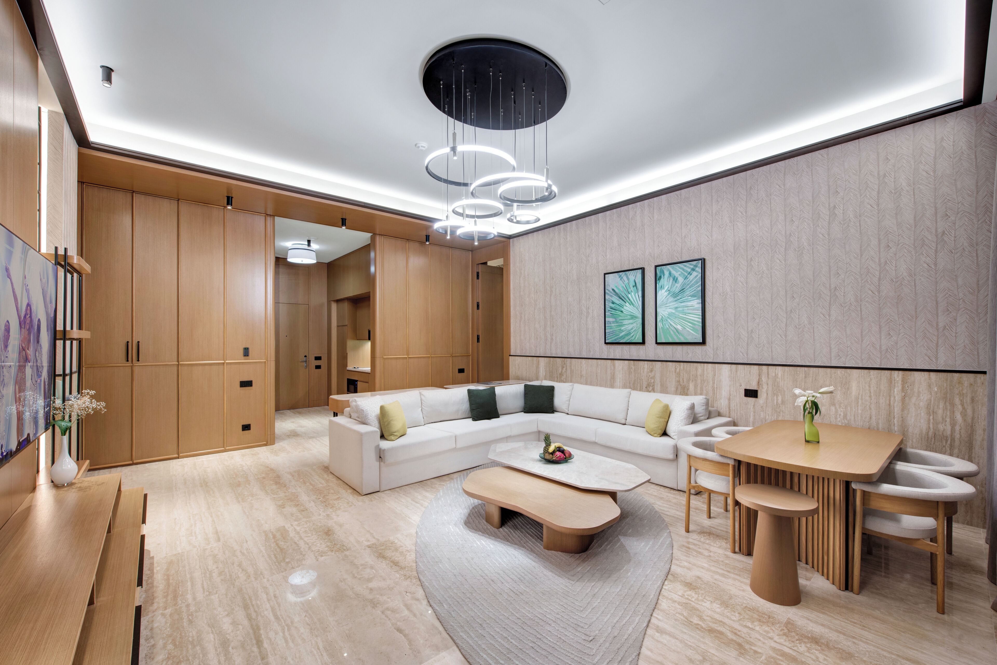 Un salon moderne avec un canapé d’angle, une table basse ronde et un coin repas comprenant une table et des chaises en bois.