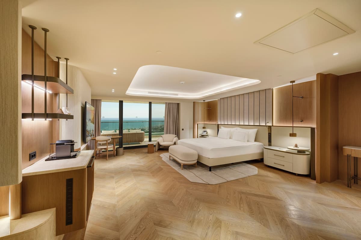 Ein modernes Schlafzimmer mit einem großen Bett, einem Schreibtisch und Blick auf das Meer.