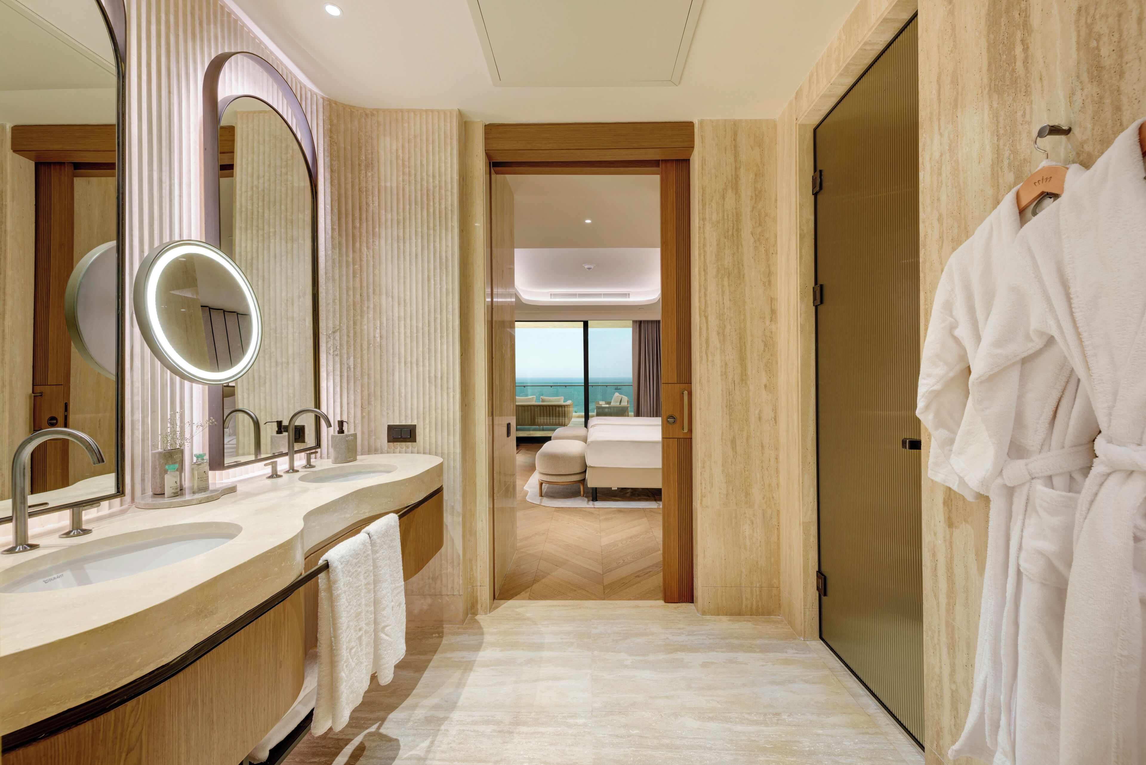 Une salle de bain moderne avec deux vasques, un grand miroir et un peignoir accroché au mur.