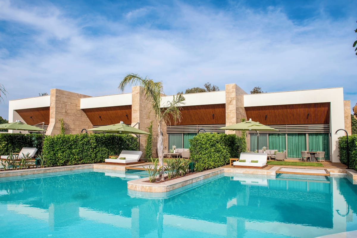 Ein modernes Hotel mit Swimmingpool, Liegestühlen und Sonnenschirmen.