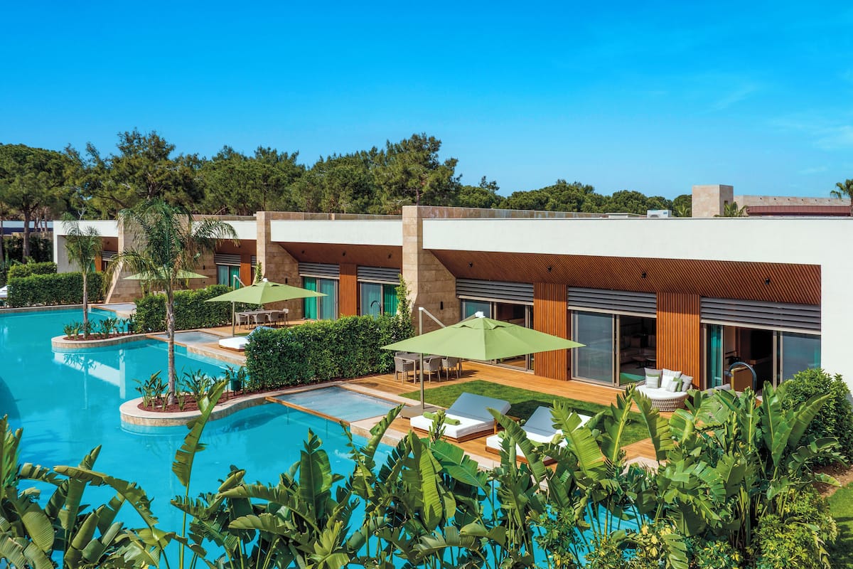 Ein modernes Resort mit Schwimmbad, Sitzgelegenheiten im Freien und üppiger Bepflanzung.
