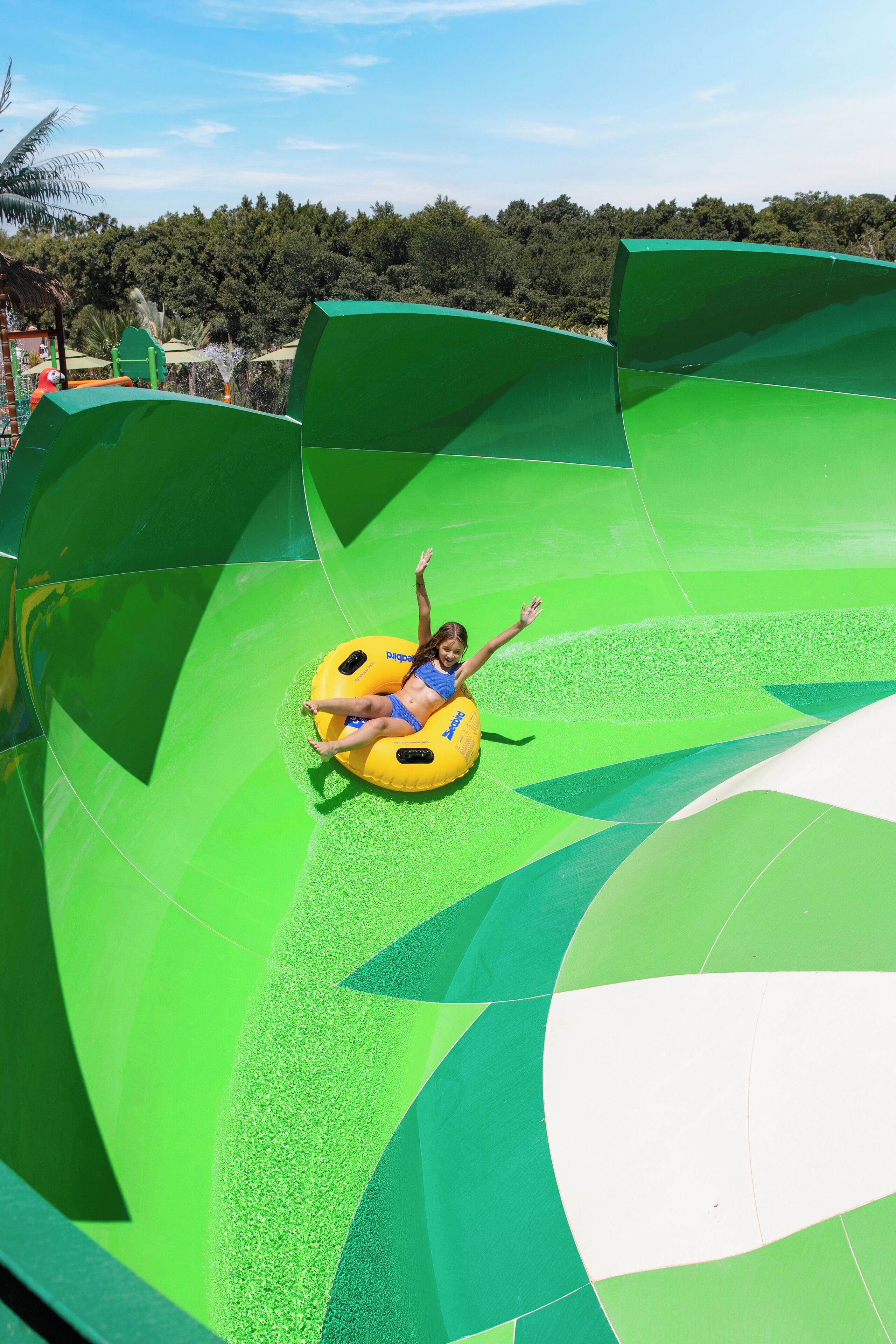 A person on a yellow tube in a green water slide.