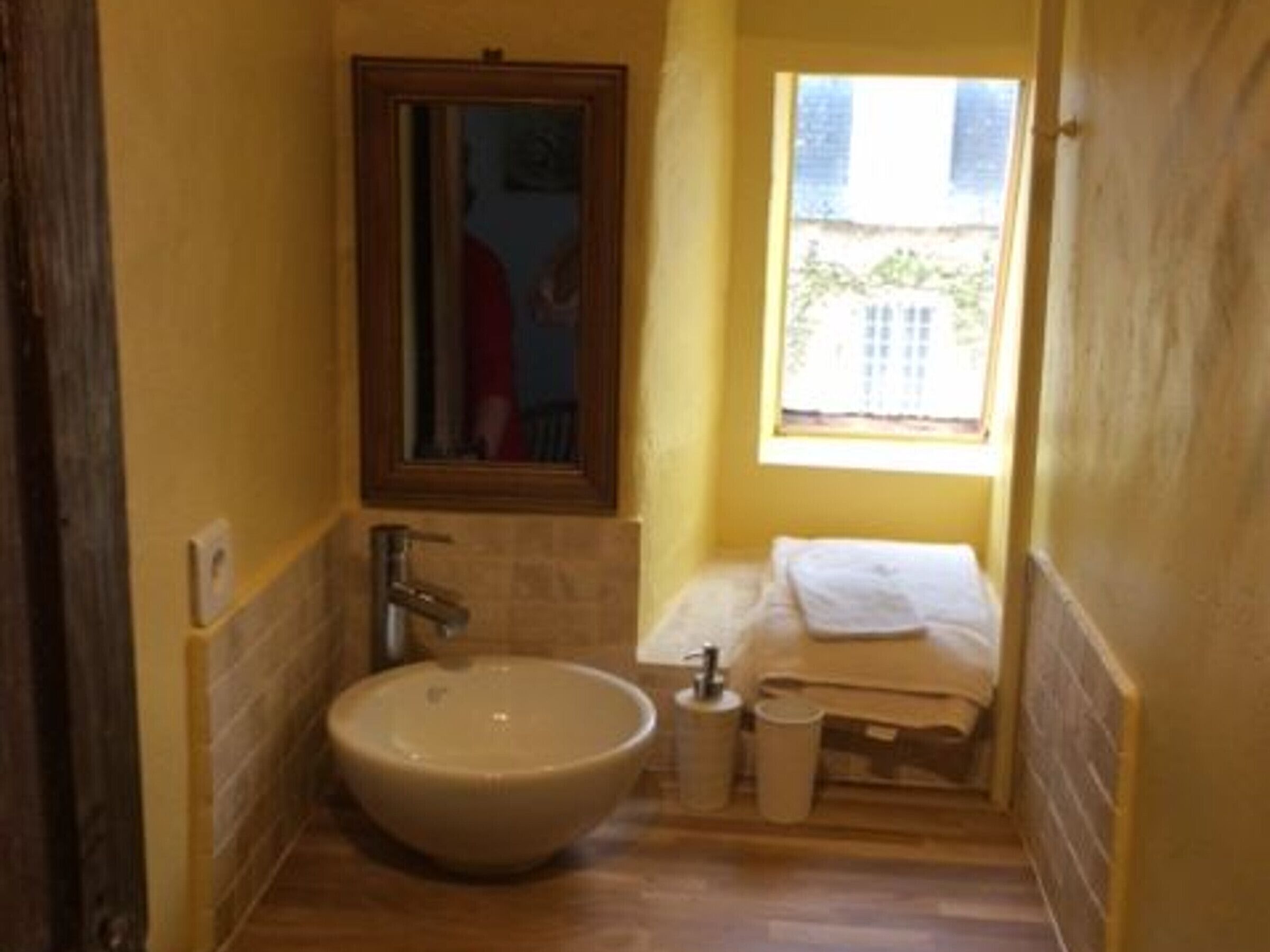 Un baño estrecho con un lavamanos grande, un espejo y una ventana.