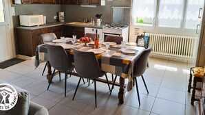 A modern kitchen with dark wooden cabinets, a built-in microwave, and a gas stove. There is a dining area with a table set for four, surrounded by chairs.