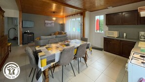 A cozy kitchen with a dining area, wooden ceiling, and a view of the outdoors.