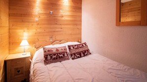 Une pièce chaleureuse en bois, avec un lit, une table de chevet et un miroir fixé au mur.