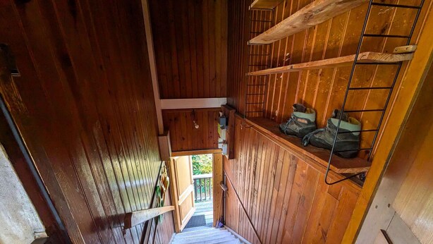 A wooden staircase leading to a landing with a view of greenery outside. - 2-bedroom apartment, 5 guests, village center with parking (Arêches-Beaufort)