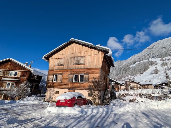 Une cabane en bois, dotée d’un toit en pente, entourée d’un paysage enneigé et de montagnes.