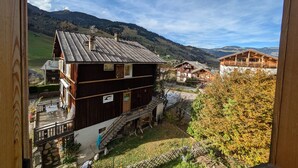 A wooden chalet with a balcony, a staircase, and a view of a mountainous landscape. - 2-bedroom apartment, 5 guests, village center with parking (Arêches-Beaufort)
