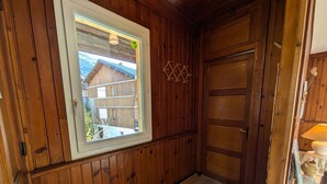 A wooden interior with a window, a door, and a lamp. - 2-bedroom apartment, 5 guests, village center with parking (Arêches-Beaufort)