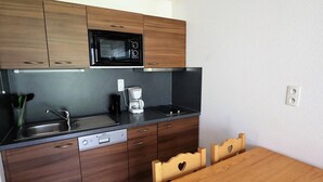 Una cocina compacta equipada con microondas, cafetera y lavavajillas.
