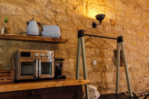A kitchen with a built-in oven, a coffee maker, and a hanging rack.