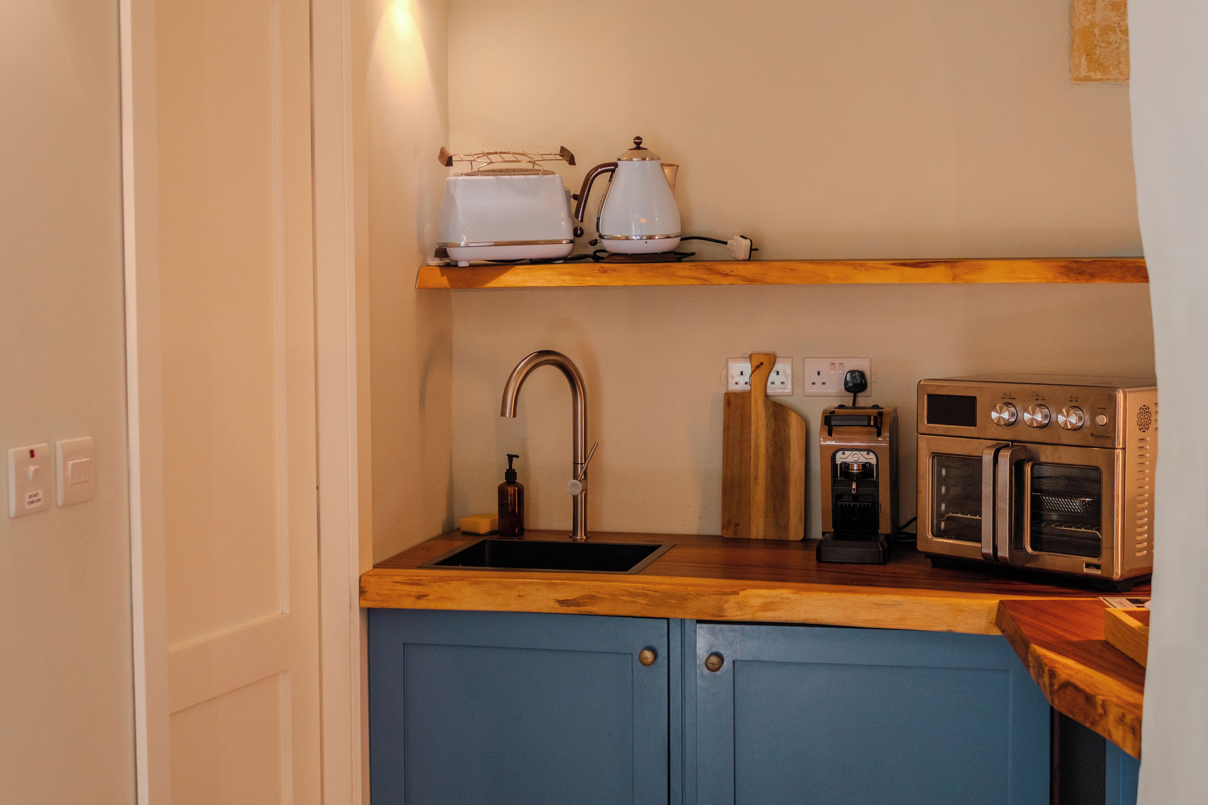 Una cocina equipada con un lavamanos, tostadora, hervidor, cafetera y horno.