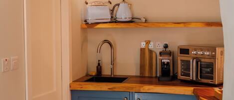 A kitchen with a sink, toaster, kettle, coffee maker, and oven.