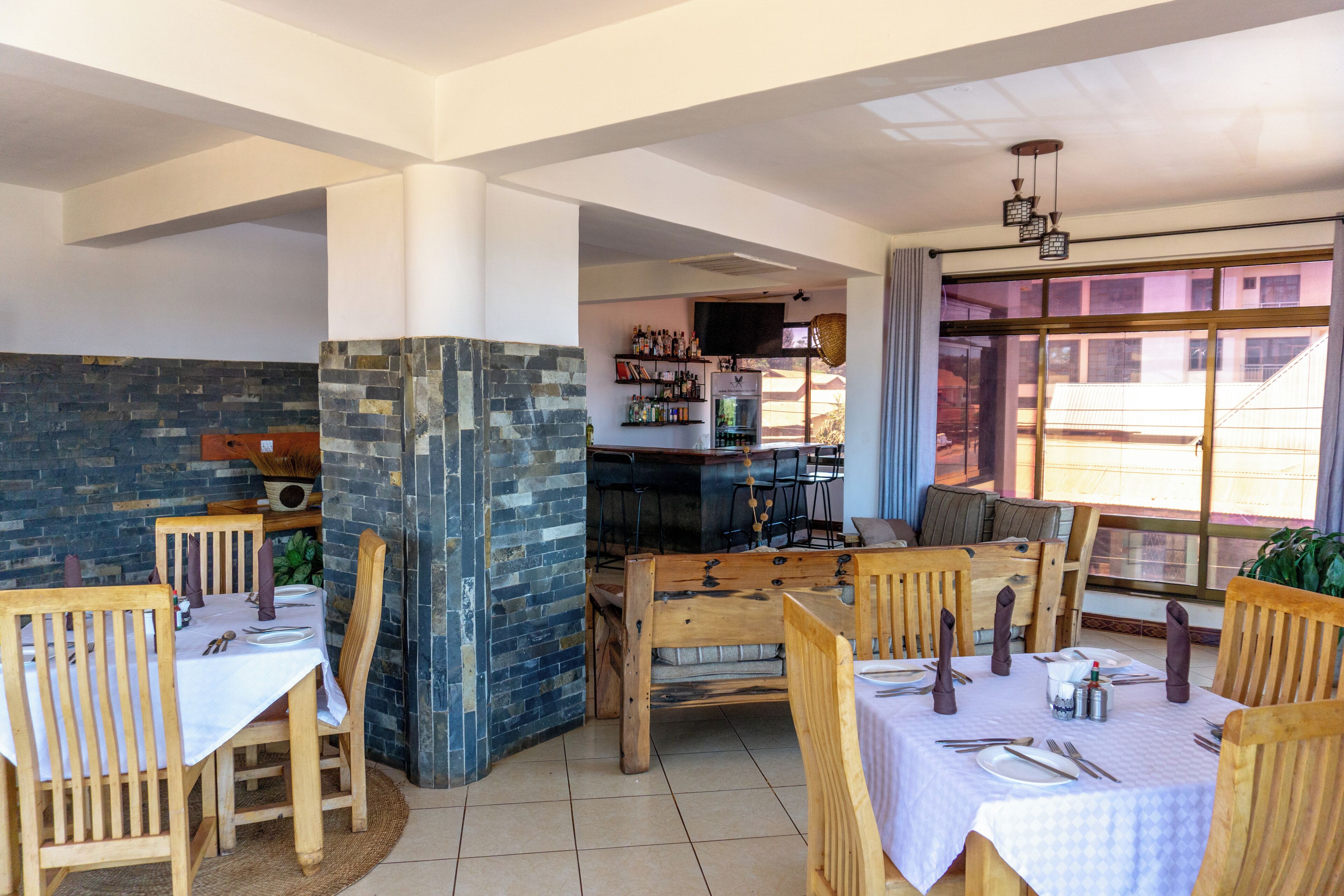 Un restaurant avec des tables et des chaises en bois, des murs en pierre et un bar avec des étagères remplies de bouteilles.