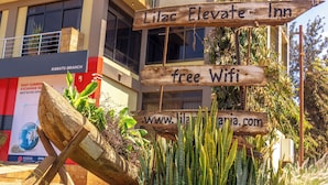 Une enseigne en bois portant l’inscription « Lilac Elevate Inn » et la mention « Wi-Fi gratuit », indiquant le nom de l’établissement et les services qu’il propose.