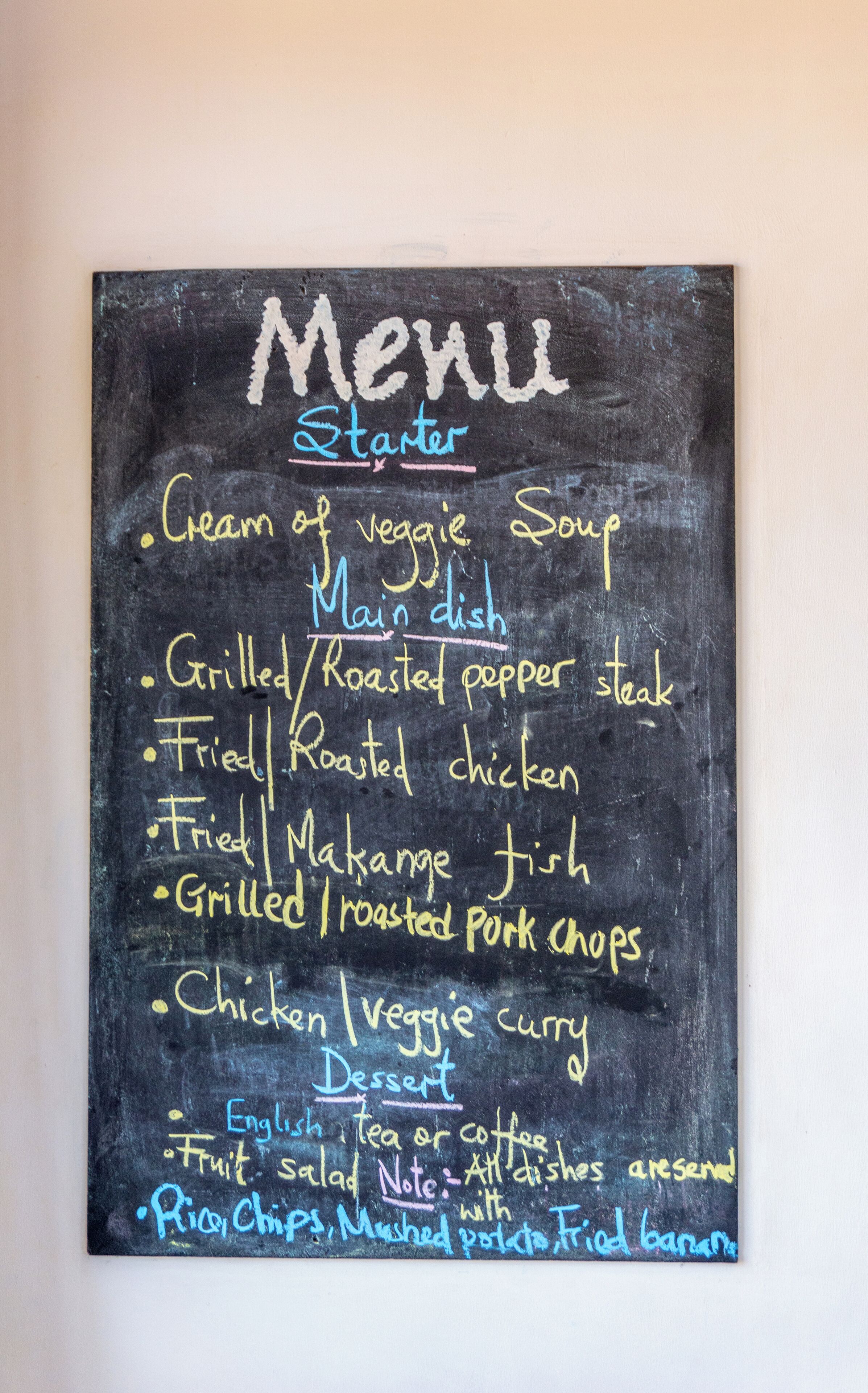 A chalkboard menu listing various dishes such as grilled steak, roasted chicken, and veggie soup.