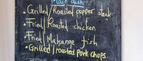 A chalkboard menu listing various dishes such as grilled steak, roasted chicken, and veggie soup.